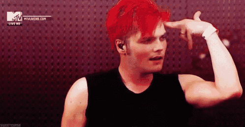 a man with red hair is pointing at his head