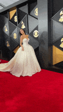 a woman in a white dress is on a red carpet