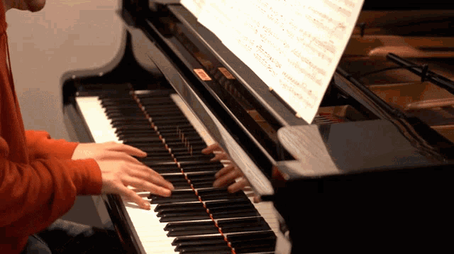 a person playing a piano with a sheet of music behind them