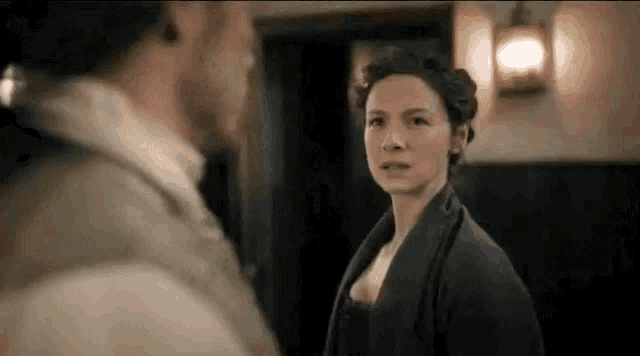 a man and a woman are standing next to each other in a room looking at each other .