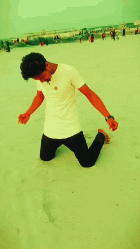 a man in a white shirt is kneeling down on the sand