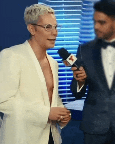 a man in a tuxedo is talking into a microphone with the letter m on it