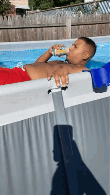 a man is laying in a swimming pool drinking a beer