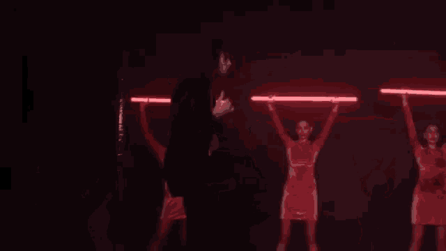 a man in a black coat is standing in front of a group of red lights