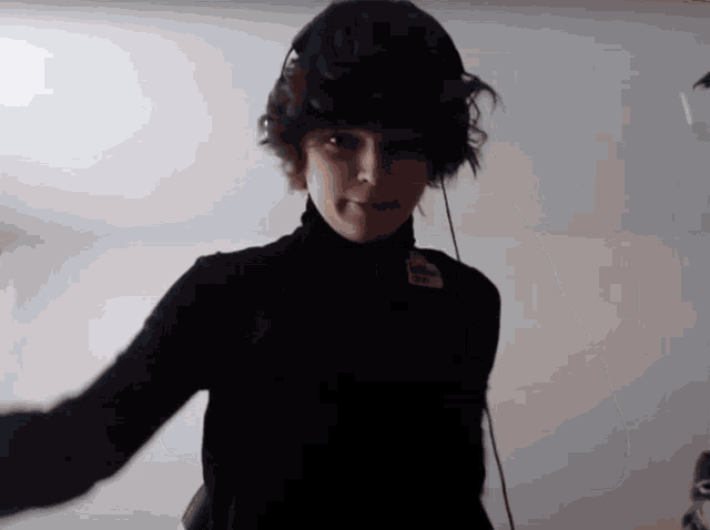 a person wearing a black turtleneck and headphones with the letter c on their chest