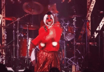 a person in a red clown costume is dancing on a stage .