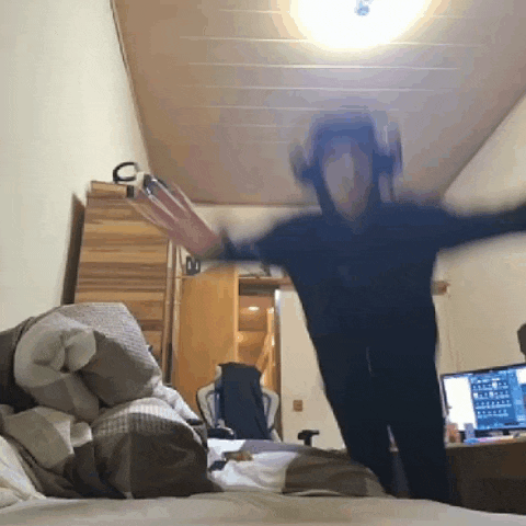 a person is standing on a bed with their arms outstretched in front of a computer monitor