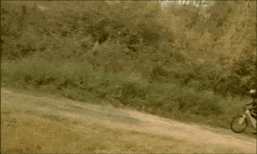 a bicycle with a basket on the back is parked on a dirt path