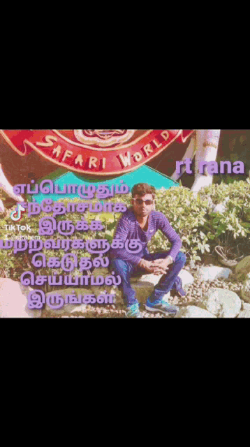a man sits on a rock in front of a sign that says safari world