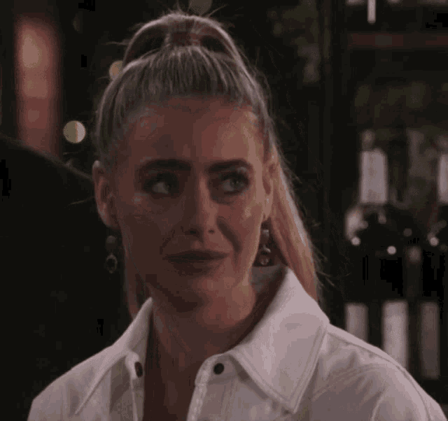 a woman with a ponytail and earrings looks at the camera
