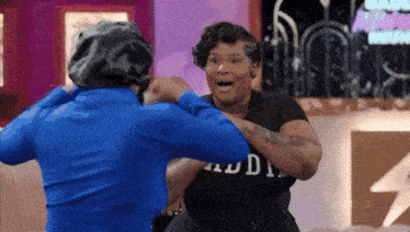a woman in a black shirt with the word audi on it is fighting another woman in a blue shirt