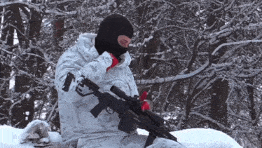 a man wearing a mask holds a rifle in the snow