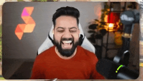 a man with a beard is sitting in a chair with his eyes closed and laughing .