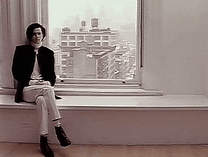 a man is sitting on a window sill in front of a window .