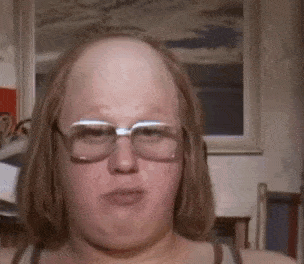 a woman with glasses and a bald head looks at the camera .