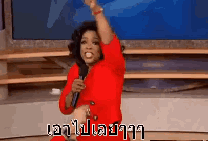 a woman in a red dress is holding a microphone and raising her fist .