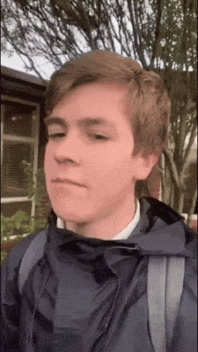 a young man wearing a blue jacket with a backpack