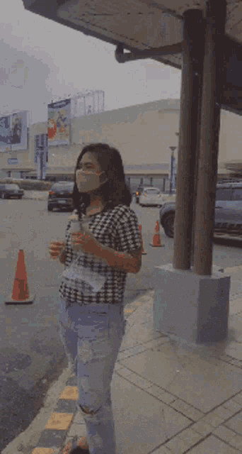 a woman wearing a face mask is holding a drink
