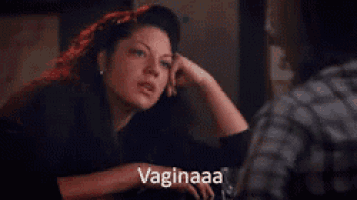 a woman with red hair is sitting at a table with her hand on her chin and the words vaginaaa written on the bottom .