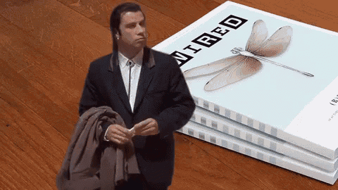 a man in a suit stands in front of a stack of wired magazines