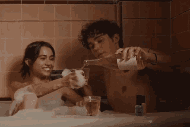 a man pours wine into a glass while a woman holds a glass