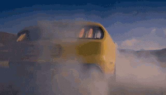 a yellow car is driving down a road with smoke coming out of its tires