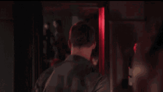 a man in a dark room with a red light behind him