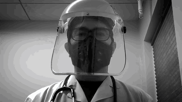 a black and white photo of a doctor wearing a gas mask and a face shield
