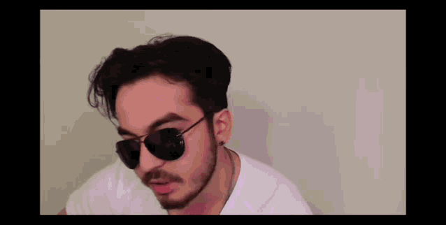 a man with a beard wearing sunglasses and a white t-shirt