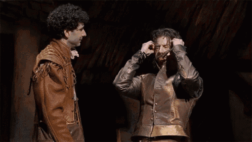 two men in costume are standing next to each other on a stage .