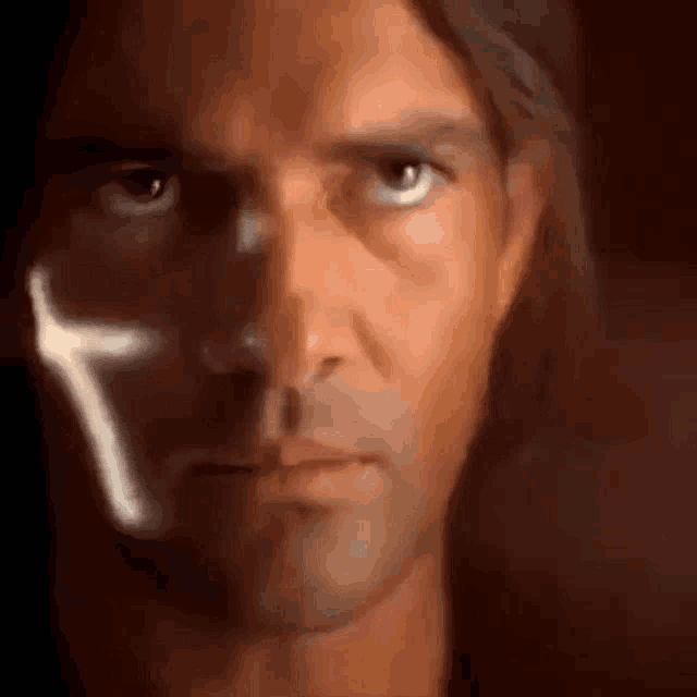 a close up of a man 's face with a cross behind it