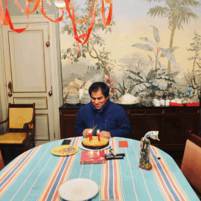 a man sitting at a table with a cake and candles on it