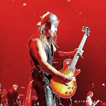 a man wearing a helmet plays a guitar on a stage