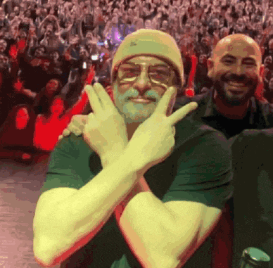 a man wearing a beanie and glasses is giving the peace sign