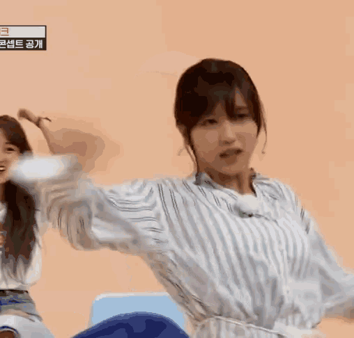 a woman in a striped shirt is dancing while another woman looks on .