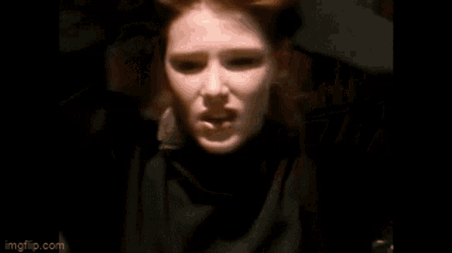 a woman with red hair is wearing hoop earrings and a black turtleneck sweater .