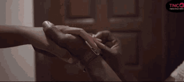 a man is holding a woman 's hand in front of a door .