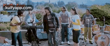 a group of people are standing around a drum set and a piano .