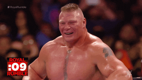 a man with a tattoo on his chest stands in front of a crowd and a sign that says royal rumble on it