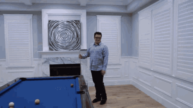 a man stands in front of a pool table in a room