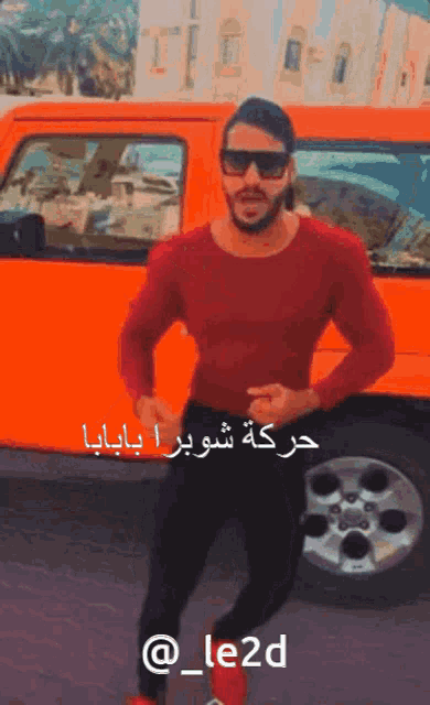 a man wearing sunglasses stands in front of an orange van