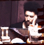 a man with a beard is sitting at a table with his hand on his chin