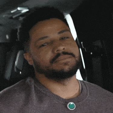 a man with a beard wears a necklace with a green stone