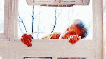 a man is looking out of a window while holding a fork .