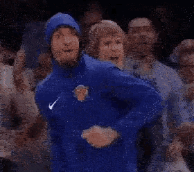 a man in a blue jacket is dancing in a crowd of people