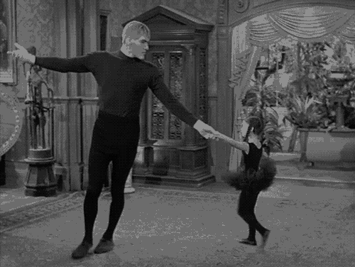 a black and white photo of a man and a little girl holding hands while dancing .