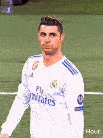 a man wearing a fly emirates jersey stands on a soccer field