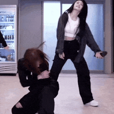 two women are dancing in front of a fridge that says etop on it