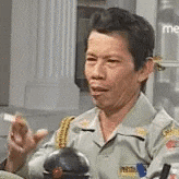 a man in a military uniform is smoking a cigarette while sitting at a table .