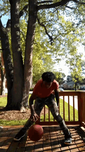 a man in a red shirt is holding a basketball on a deck